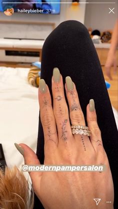 a woman's hand with tattoos on it and her nails in front of the tv