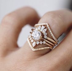 a woman's hand holding a gold ring with diamonds on it