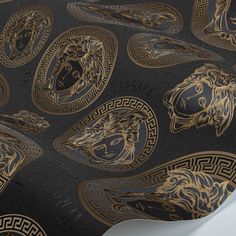 a black and gold wallpaper with lions on it's face, surrounded by greek meanies