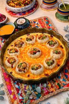 a table topped with lots of food on top of a colorful place mat next to cups and sauces