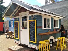 a small blue and white house with yellow stools