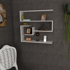 a white chair sitting in front of a wall mounted shelf with books and pictures on it