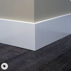 the corner of an empty room with wood flooring