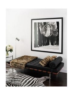 a black and white room with zebra rugs on the floor, framed photograph above bed