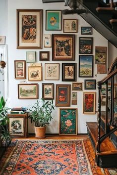 a staircase with many framed pictures on the wall and a potted plant next to it