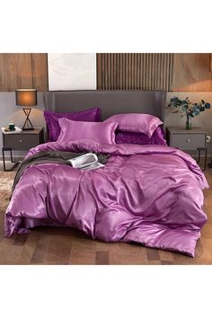 a bed with purple sheets and pillows in a room