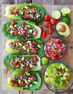 lettuce wraps filled with various vegetables and toppings on a cutting board next to two bowls of salsa