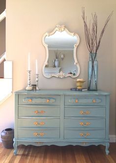 a blue dresser with flowers and candles on top