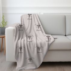 a couch with a blanket on top of it in front of a white wall and wooden floor