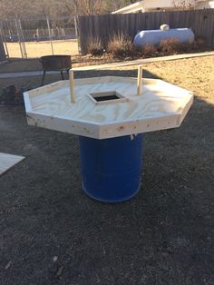 a blue barrel sitting in the middle of a yard