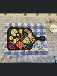 a cross - stitch picture of a dish on a blue and white checkered tablecloth