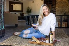 a woman sitting on the floor with a glass of wine and bread in front of her