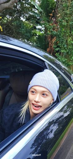 a woman sitting in the driver's seat of a car wearing a beanie