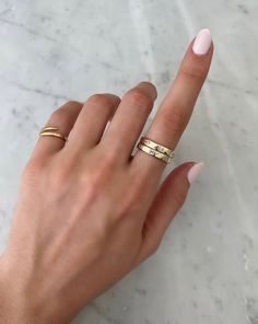 a woman's hand with two gold rings on her left and one in the middle