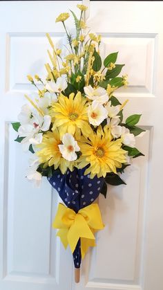 a bouquet of yellow and white flowers hanging on a door handle with polka dot ribbon