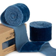 a roll of blue velvet ribbon next to a cardboard box