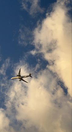 an airplane is flying in the sky with some clouds behind it and blue skies above