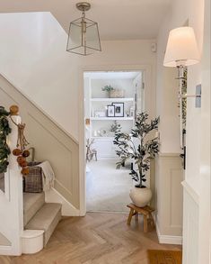 an entry way with stairs and potted plants on the steps leading to another room