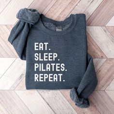 Elevate your everyday pullover with our Eat Sleep Pilates Repeat sweatshirt.  Made from a breathable, luxuriously soft fabric with a premium printed design. Featuring a crewneck style and a relaxed, lightweight fit for a comfort that goes everywhere with you. Feels like a cloud, looks like a day off. The perfect cozy essential or gift. DETAILS: -Premium cotton blend -Premium printed detail across left chest -Finished with ribbed collar, cuff & hem -Brushed inner fleece for added softness -If you Long Sleeve Workout Tops With Text Print, Pilates Workout Clothes, Pilates Shirt, Yoga Workout Clothes, Yoga Sweatshirt, Pilates Clothes, Sweatshirt Details, Pilates Instructor, Crewneck Style