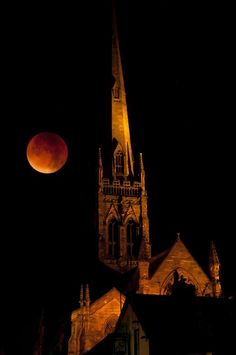 the blood moon is seen in front of an old church