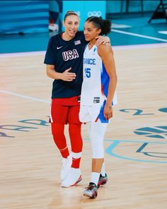 two female basketball players standing next to each other on a court with their arms around each other