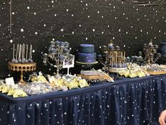 a table topped with cakes and desserts covered in frosted stars on a black wall