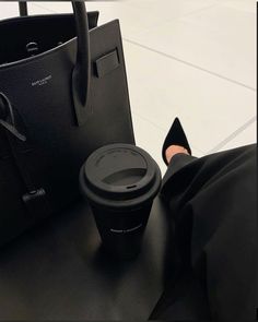 a woman's legs and handbag sitting on top of a black leather table