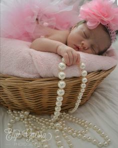 a baby is sleeping in a basket with pearls on the floor and wearing a pink tutu