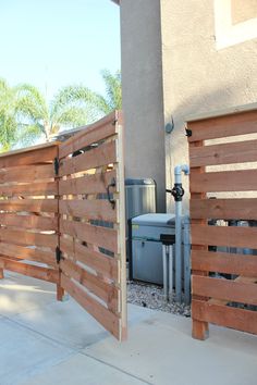 a wooden gate is open on the side of a building with an air conditioner in the background