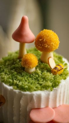 there is a small cake with tiny mushrooms on the top and green frosting around it