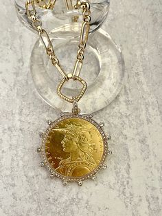 Beautiful reproduction vintage coin pendant, French Madagascar coin in a bezel with cubic zirconia stones. The bale attached to the coin is also encrusted with CZ stones. The coin is 22k gold plated and elegantly hangs from a multi link gold plated brass chain and a rope design spring lock clasp. The spring lock closure not only makes it easy to open and close the necklace for those with difficulty but adds to the creativity of the jewelry piece. Please see photograph of how to open the clasp. W Luxury Yellow Gold Coin Medallion Necklace, Luxury Gold Coin Medallion Necklace, Yellow Gold Coin Necklace For Anniversary, Luxury Engraved Coin Necklace, Antique Gold Necklace With Diamond Accents, Luxury Yellow Gold Coin Pendant Necklace, Gold Round Coin Necklace For Anniversary, Antique Gold Round Coin Necklace, Diamond Coin Pendant Jewelry