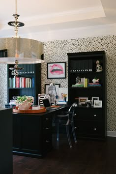 a home office with black furniture and wallpaper