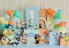 an assortment of toys and decorations for a baby's first birthday party with balloons