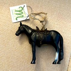 a small black horse figurine sitting on top of a couch next to a tag