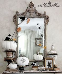 a mirror and some white pumpkins on a table