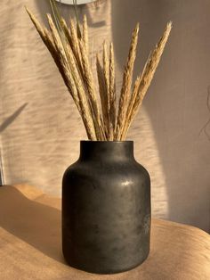 a black vase sitting on top of a wooden table