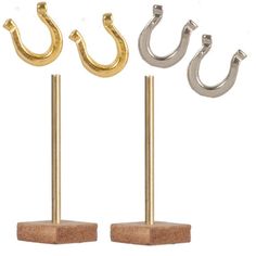 three gold and silver metal hooks on wooden bases with two smaller ones in the middle