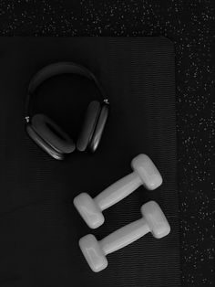 headphones and two dumbbells on a mat