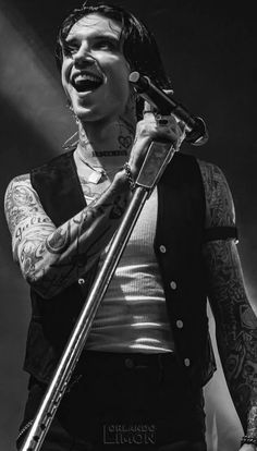 a man with tattoos and piercings holding a microphone