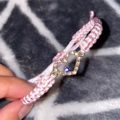 a person is holding a pink bracelet with a blue stone in the middle and a heart on it