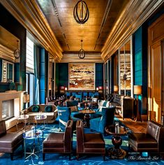 an elegant lobby with blue carpet and leather furniture in the foreground, large painting on the wall