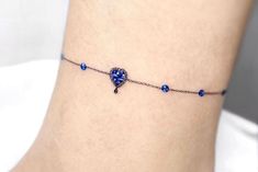 a woman's ankle with a blue beaded heart on it