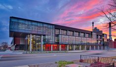 an office building sits on the corner of a street in front of a colorful sky