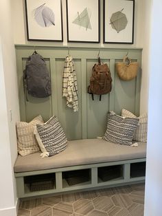 a bench with some pillows on it and pictures hanging above the bench in front of it