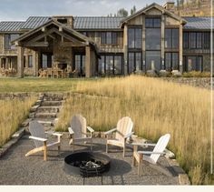 a fire pit sitting in front of a large house on top of a grass covered field