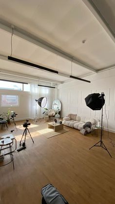 an empty room with wooden floors and lighting equipment on the floor in front of large windows