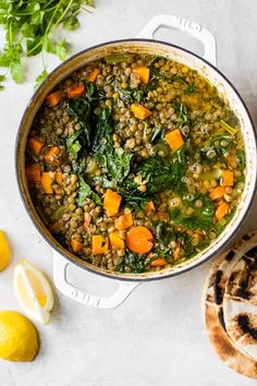 a pot filled with lentils, carrots and spinach on top of a table