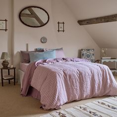 a bed in a bedroom with pink comforter and pillows