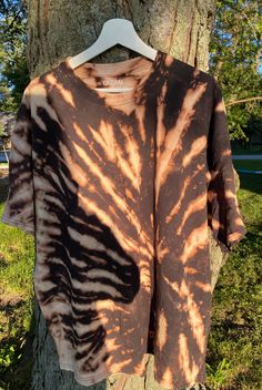 a brown and black tie dye shirt hanging on a tree