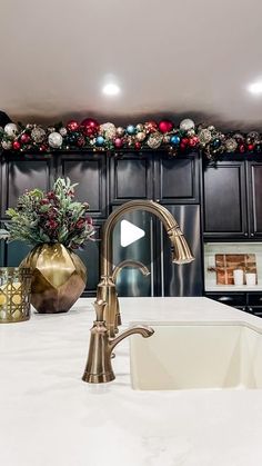 a kitchen with black cabinets and white countertops has christmas decorations on the wall above the sink